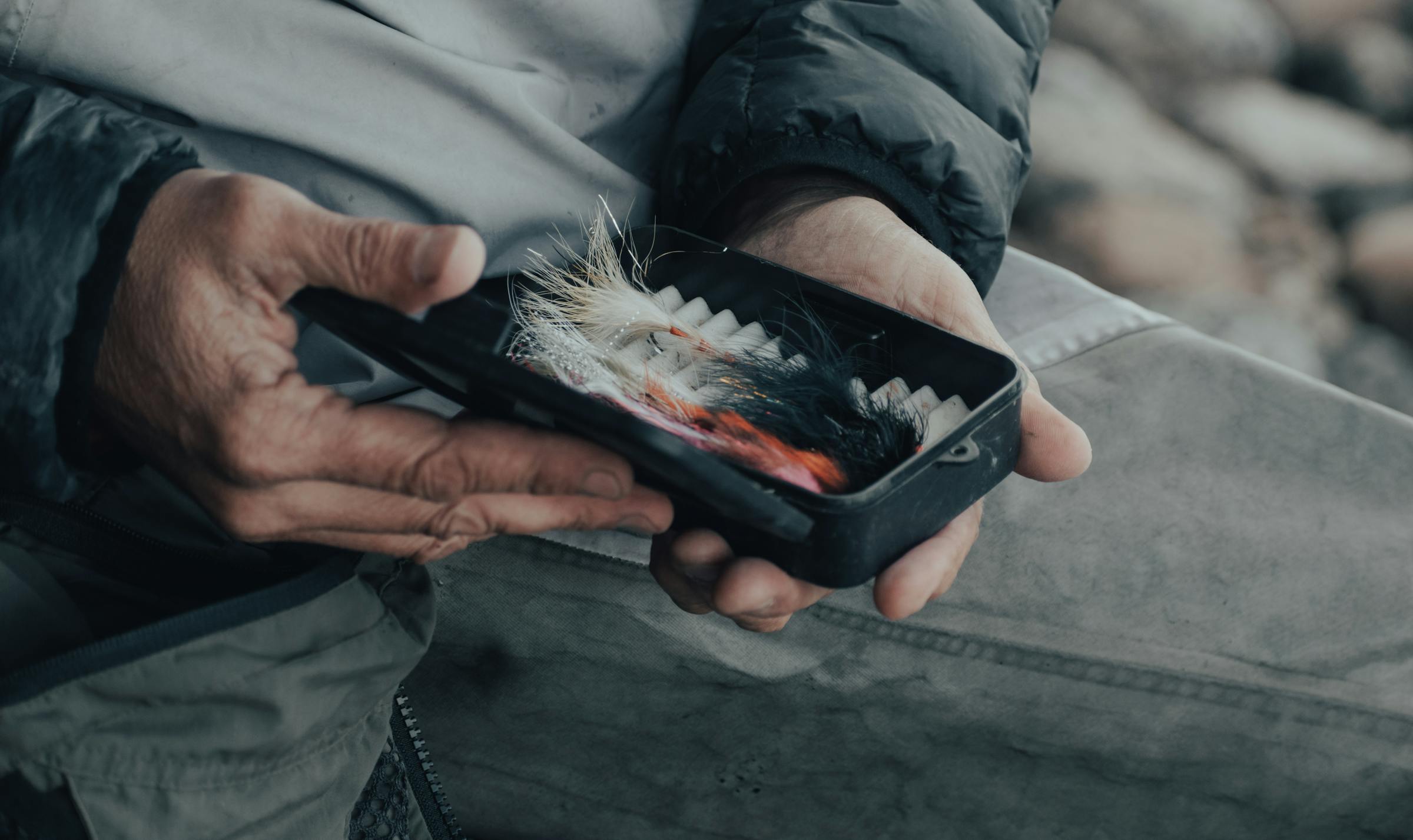 Hands choosing a fly from a fly box